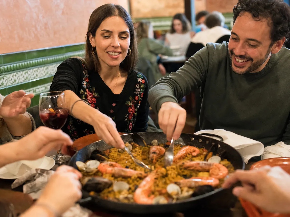 Amigos compartiendo una paella de marisco