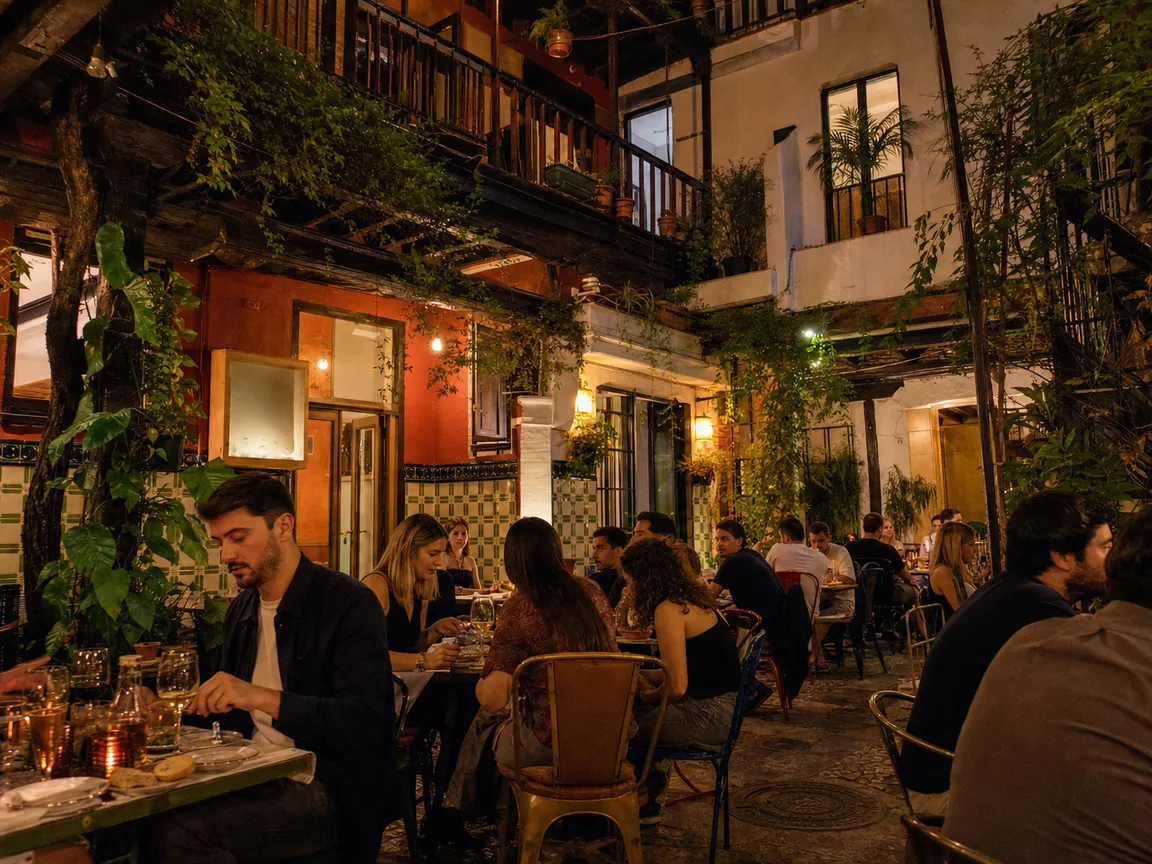 El patio de la corrala con balcones de madera y mesas preparadas
